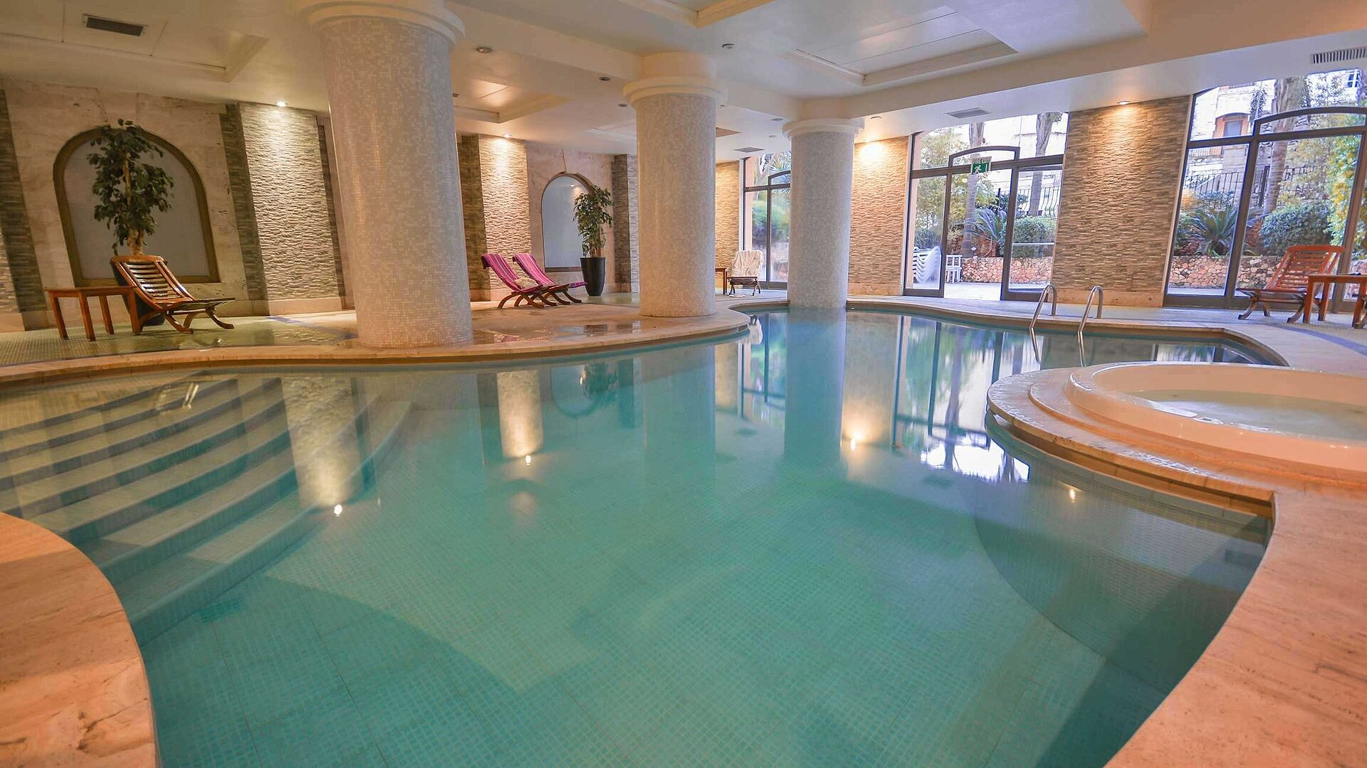 Elegant indoor pool with columns, whirlpool and relaxation area in the spa