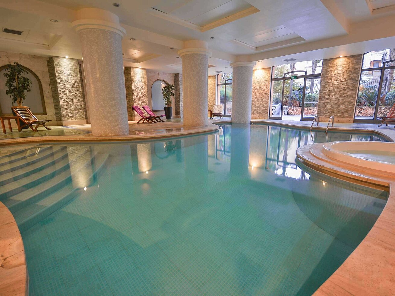 Elegant indoor pool with columns, whirlpool and relaxation area in the spa