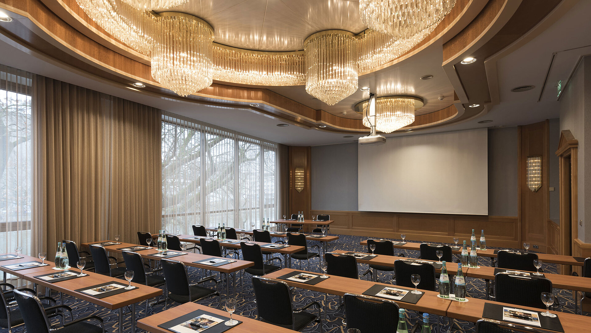 Elegant meeting room with theatre seating, chandeliers and projector screen at Maritim Hotel Ulm.