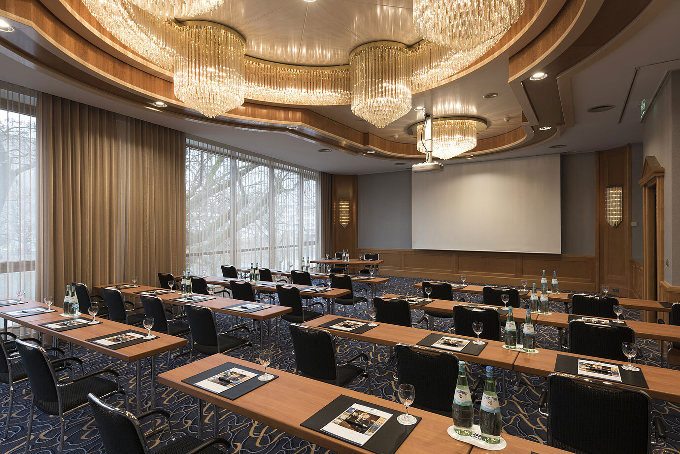 Elegant meeting room with theatre seating, chandeliers and projector screen at Maritim Hotel Ulm.