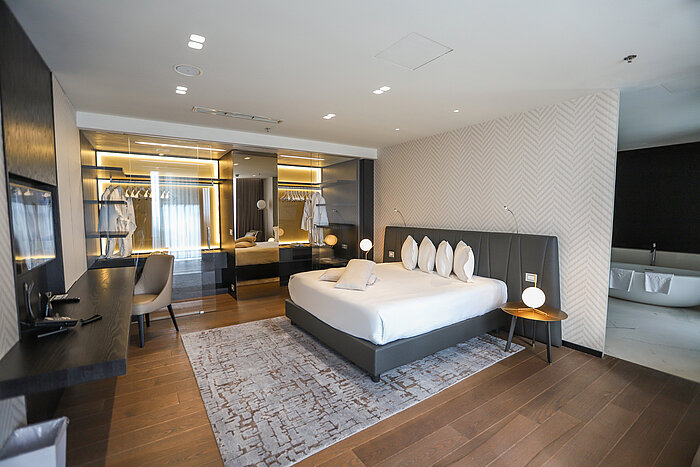Designer bedroom with spacious bed, mirror wall and dressing area at Maritim Hotel Plaza Tirana