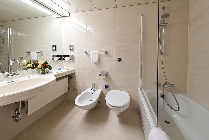 Bright, elegant bathroom with bathtub, shower, sink, and mirror at Maritim Hotel Hannover.