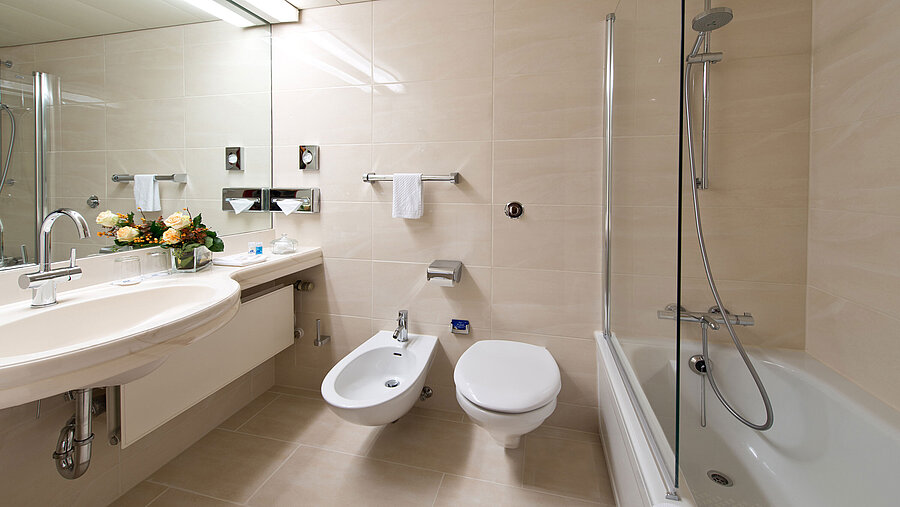 Bright, elegant bathroom with bathtub, shower, sink, and mirror at Maritim Hotel Hannover.
