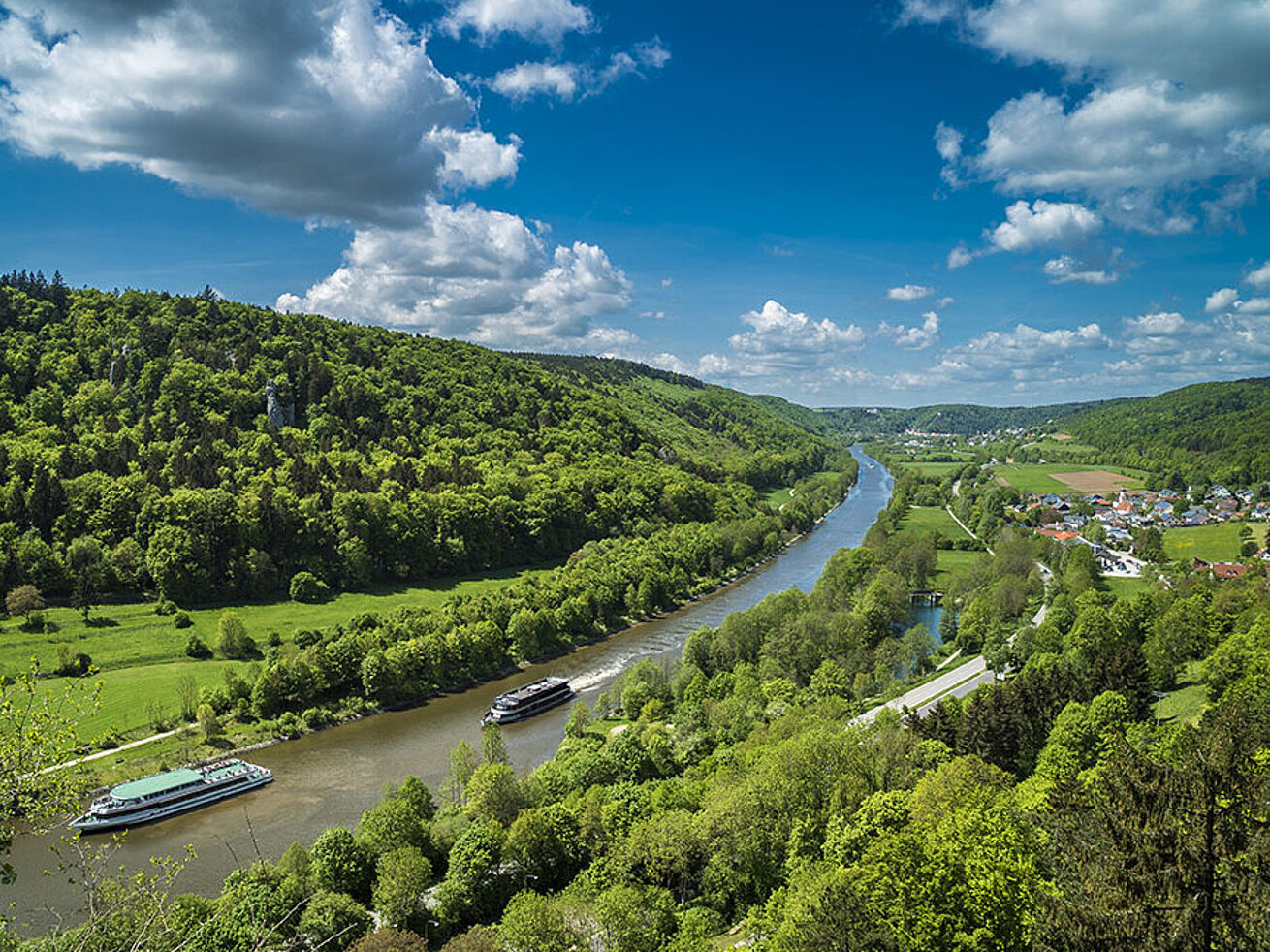 Boats on the Altmühl River in the Altmühltal, surrounded by green hills and blue sky