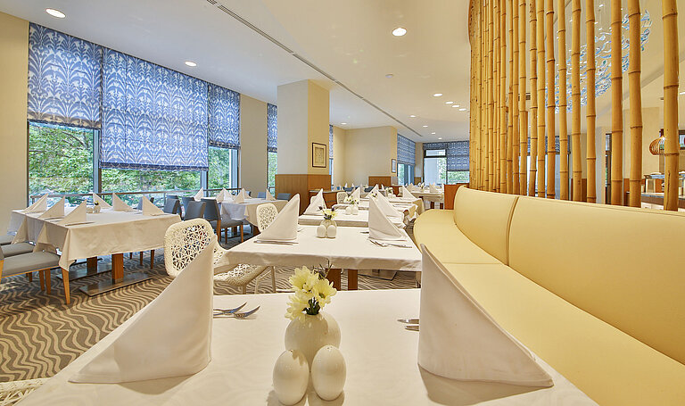 Bright restaurant with large windows, white-set tables and modern design for a relaxed dining atmosphere