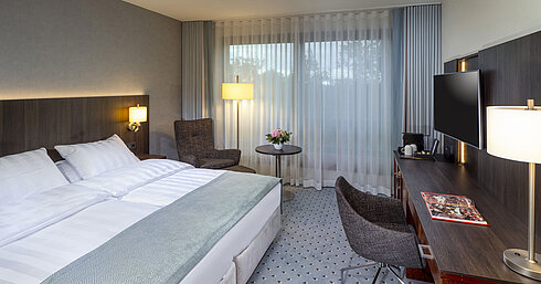 Modern Superior double room at Maritim Hotel Bremen with seating area, desk, and large window for natural light.