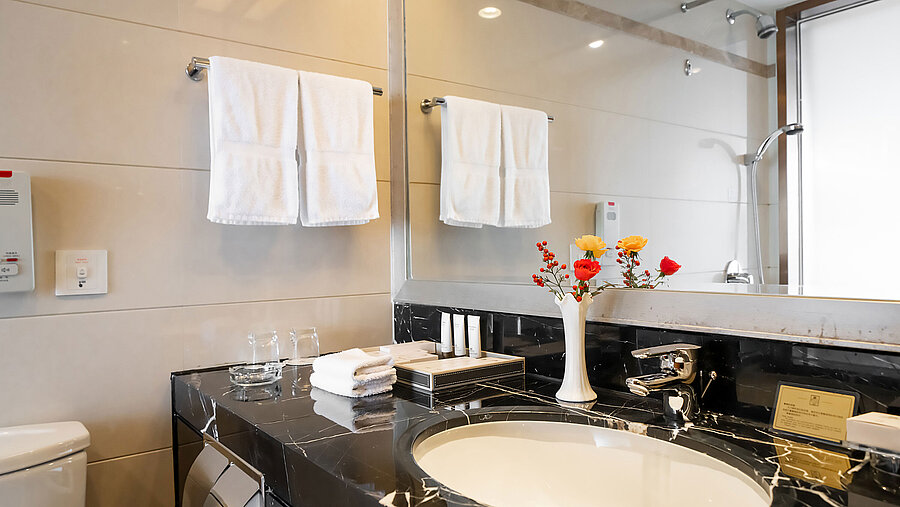 現代化酒店浴室配備深色大理石檯面、大型鏡子、潔淨毛巾及精緻衛浴用品，營造頂級氛圍