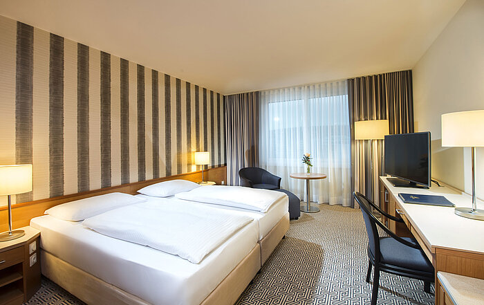 Modern double room with desk, TV and natural daylight at Maritim Hotel Stuttgart