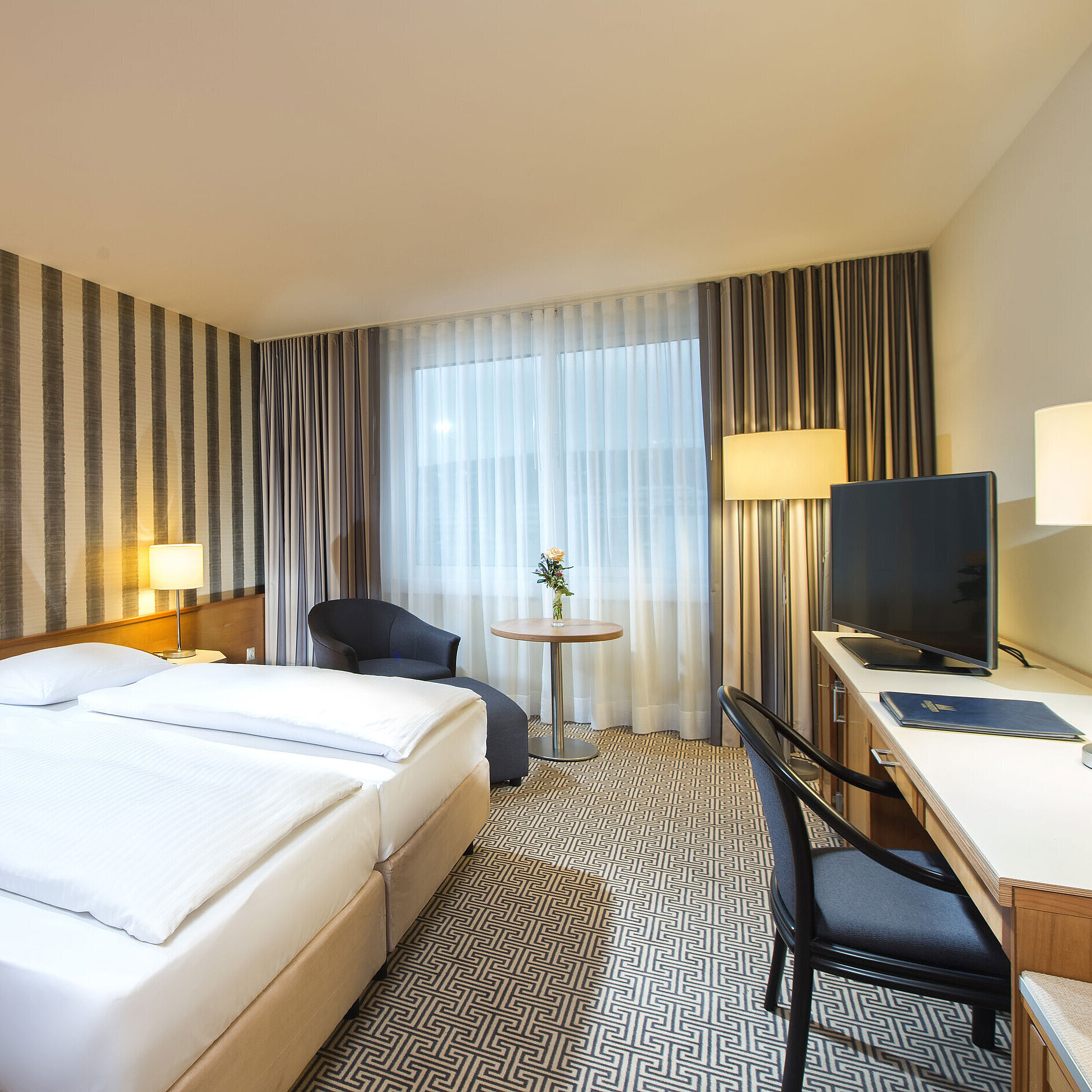 Modern double room with desk, TV and natural daylight at Maritim Hotel Stuttgart