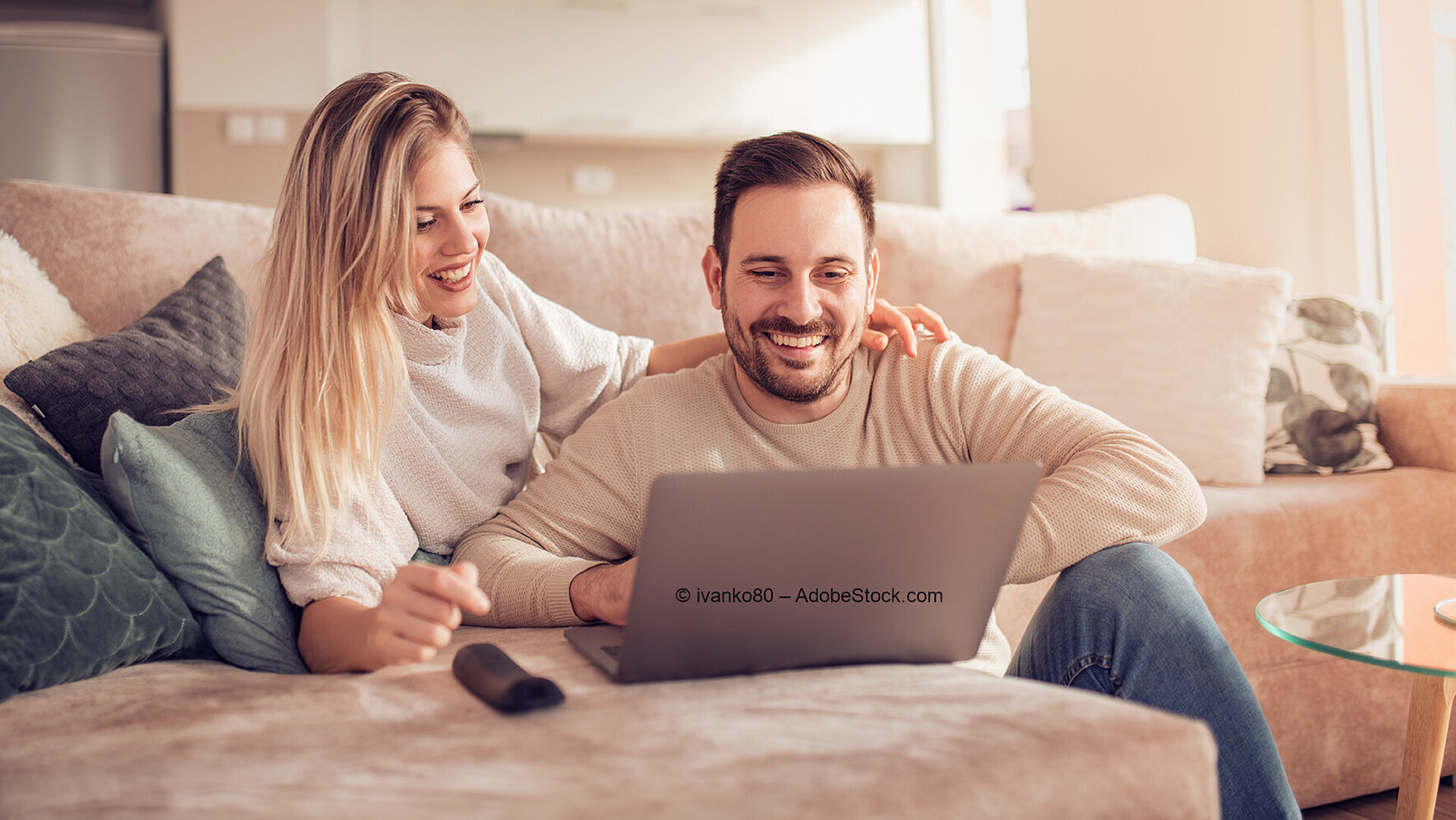 Couple relaxing on sofa while watching laptop together