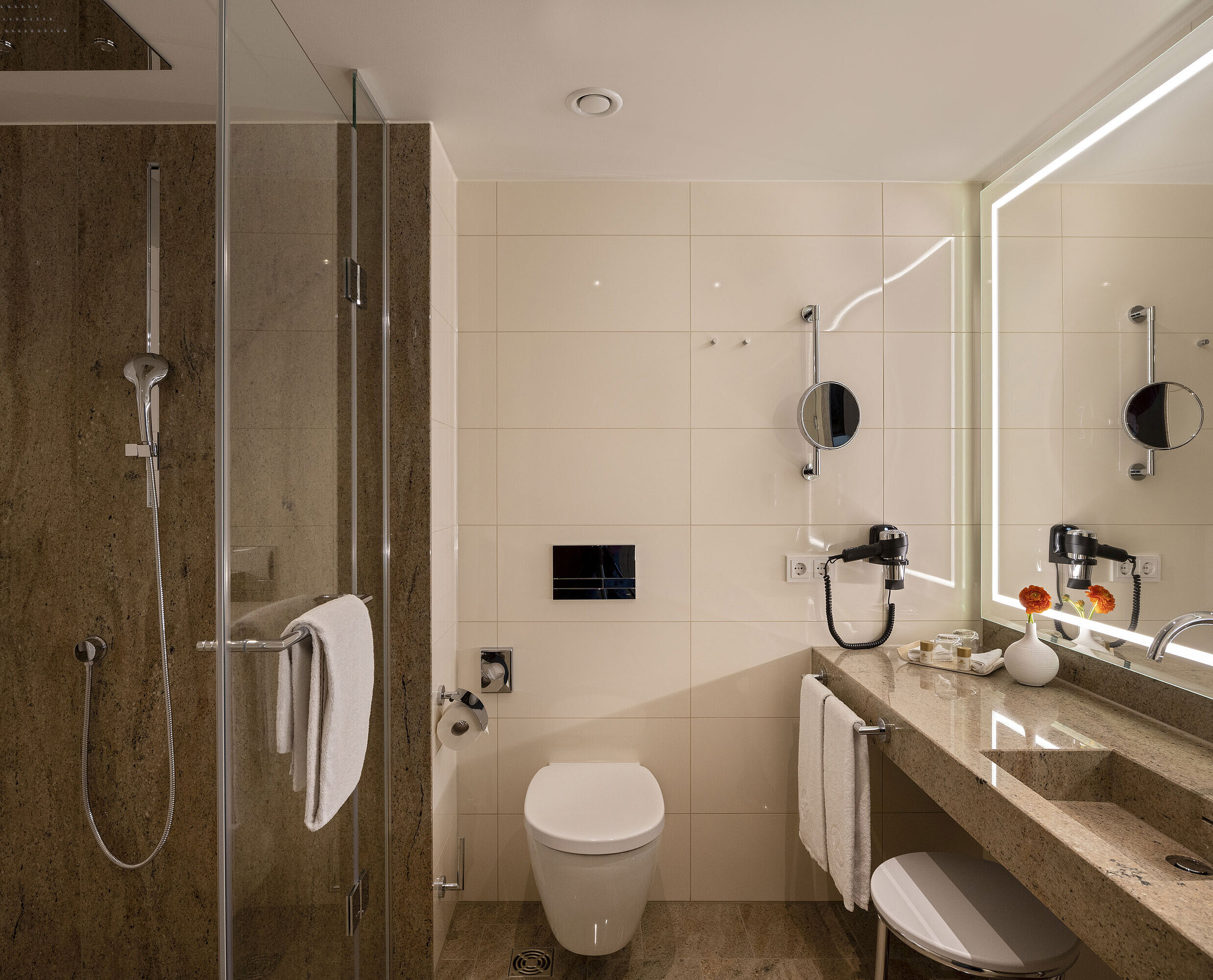 Luxurious bathroom at Maritim Hotel Ingolstadt with rain shower, double sink, and large mirrors with LED lighting.