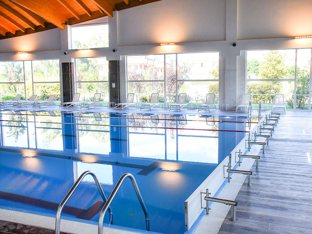 Modern indoor pool with large windows and loungers at the resort