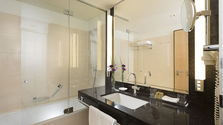 Elegant bathroom at Maritim Hotel Düsseldorf with large bathtub, mirror, sink, and modern fixtures.