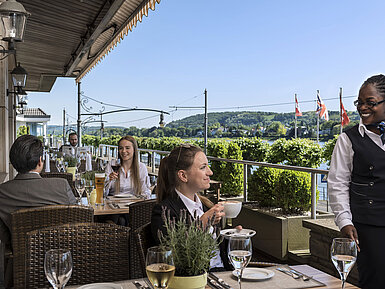Guests enjoying coffee and wine on the terrace of Maritim Hotel Königswinter with a picturesque Rhine view.
