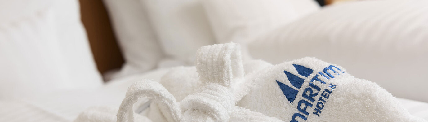 Soft bathrobe with Maritim logo on the bed at Maritim Hotel Bad Salzuflen