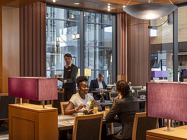 Guests enjoy breakfast at the Classico restaurant of Maritim Hotel Düsseldorf as a staff member serves drinks.