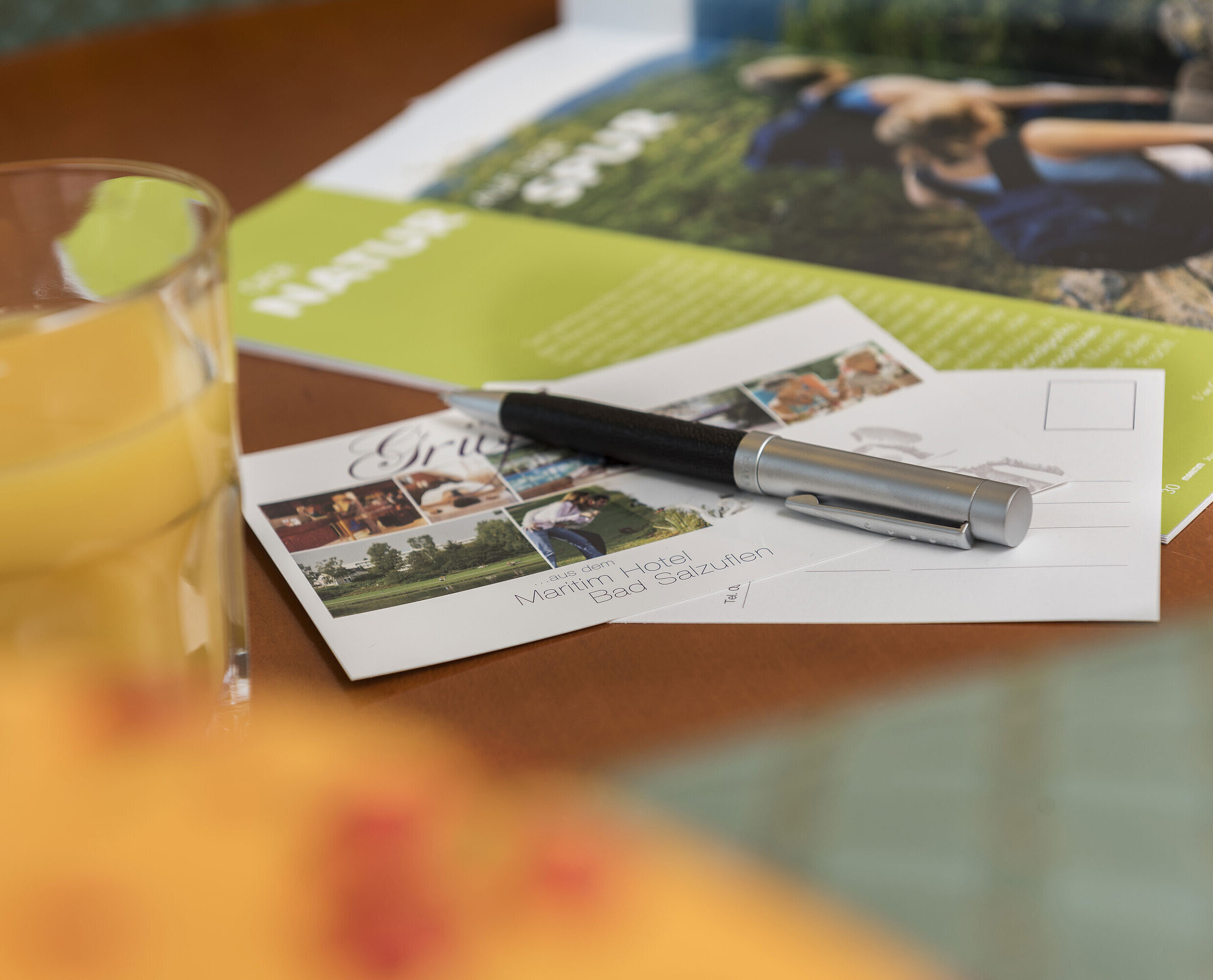 Table with postcard from Maritim Hotel Bad Salzuflen, pen, juice and brochure