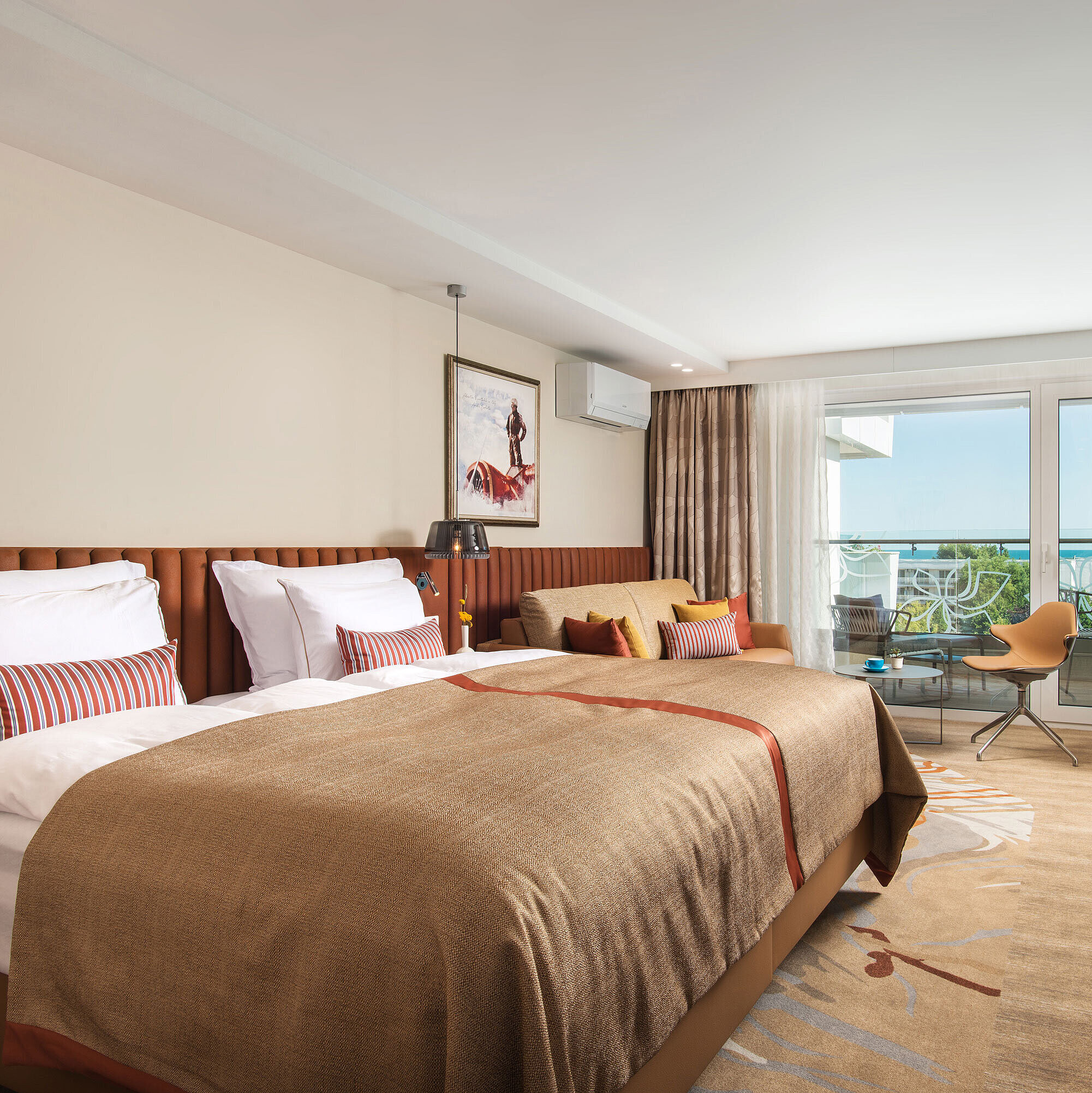 Spacious room at Maritim Hotel Amelia with cosy bed, seating area and balcony overlooking greenery