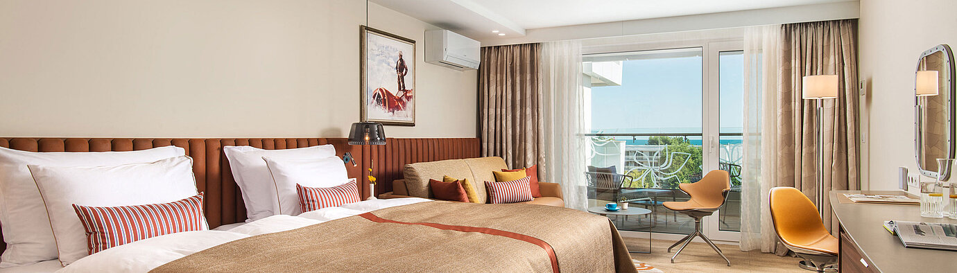 Spacious room at Maritim Hotel Amelia with cosy bed, seating area and balcony overlooking greenery