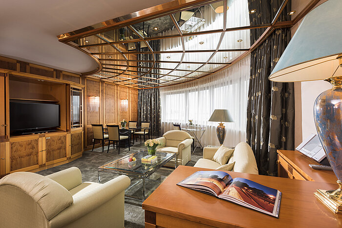 View into luxury suite with cosy seating, TV and decorative ceiling design at Maritim Hotel Magdeburg