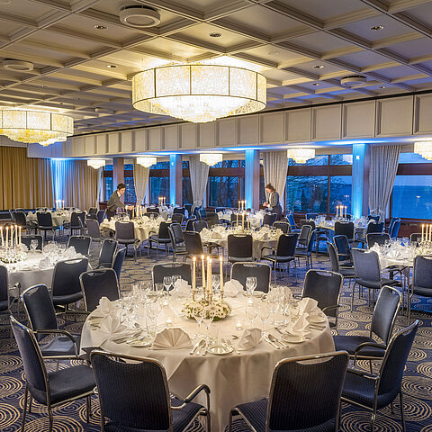 Maritim Hall in the Maritim Hotel Kiel, festively laid tables with candlelight, elegant ambience, staff preparing the event.