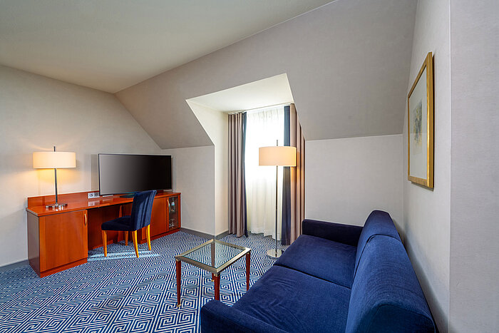 Classic Family room Living area of the Classic family room at Maritim Hotel Würzburg with sofa bed and desk