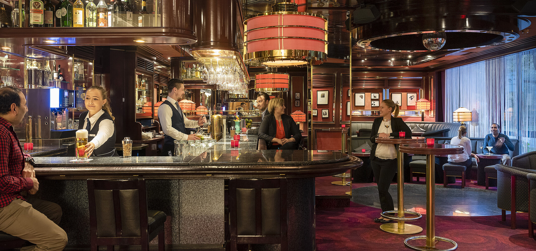 Guests enjoy drinks and a relaxed atmosphere in the stylish bar of Maritim Hotel Bremen, served by friendly staff.