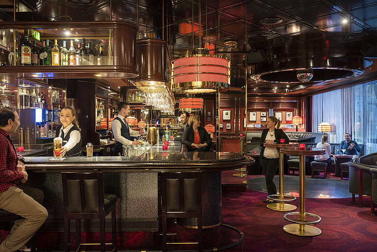 Guests enjoy drinks and a relaxed atmosphere in the stylish bar of Maritim Hotel Bremen, served by friendly staff.