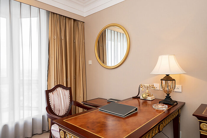 典雅經典書桌配鏡面、檯燈、裝飾性電話及窗簾窗戶，透出溫暖光線