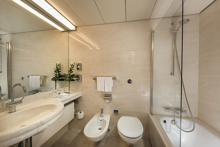 Modern bathroom with bathtub, shower, bidet, and large mirror at Maritim Hotel Hannover.