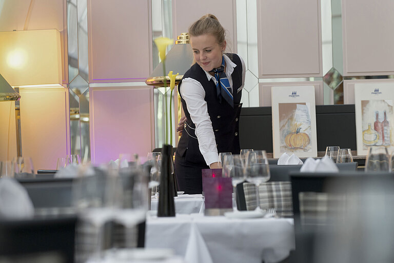 Staff member elegantly sets the table in the restaurant at the Maritim Hotel Munich
