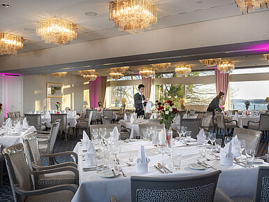 Salons Copenhagen and Helsinki in the Maritim Hotel Kiel, tables laid, chandeliers and sea view, staff arranging the room.