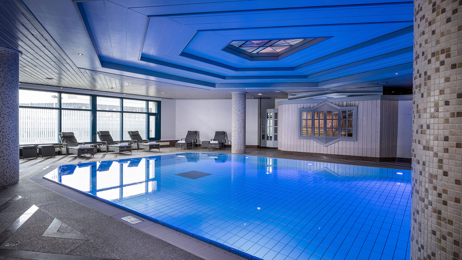 Indoor pool at Maritim Hotel Hannover with loungers and modern lighting.