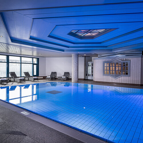 Indoor pool at Maritim Hotel Hannover with loungers and modern lighting.