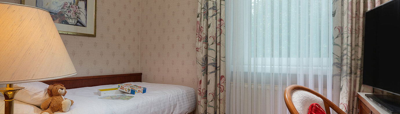 Comfort family room with single bed, toys, seating area and large window for a cosy stay.