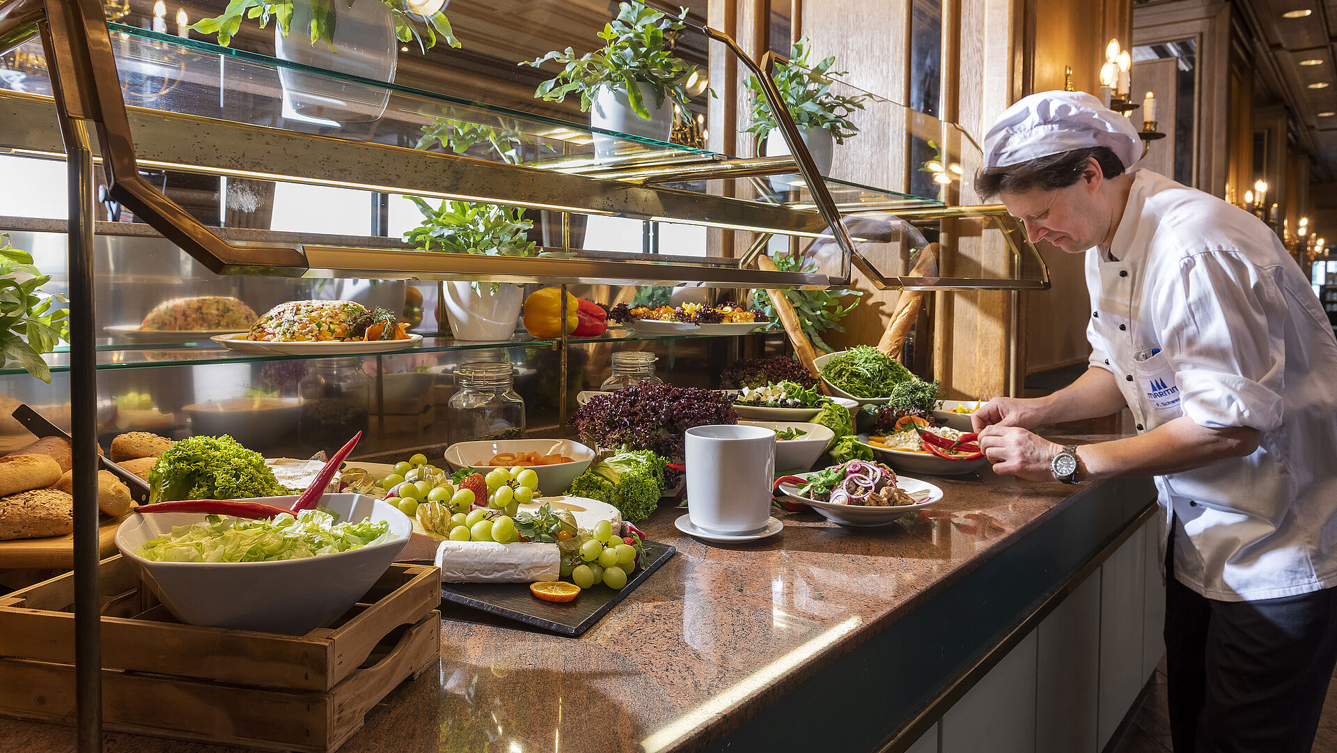 Chef preparing a fresh salad and vegetable buffet at the restaurant of Maritim Hotel Travemünde