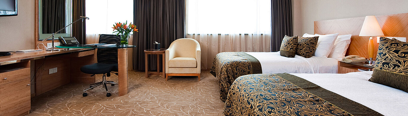 現代化酒店客房配備兩張床鋪、寬敞書桌、舒適扶手椅及充足自然光線，為您提供舒適的住宿體驗