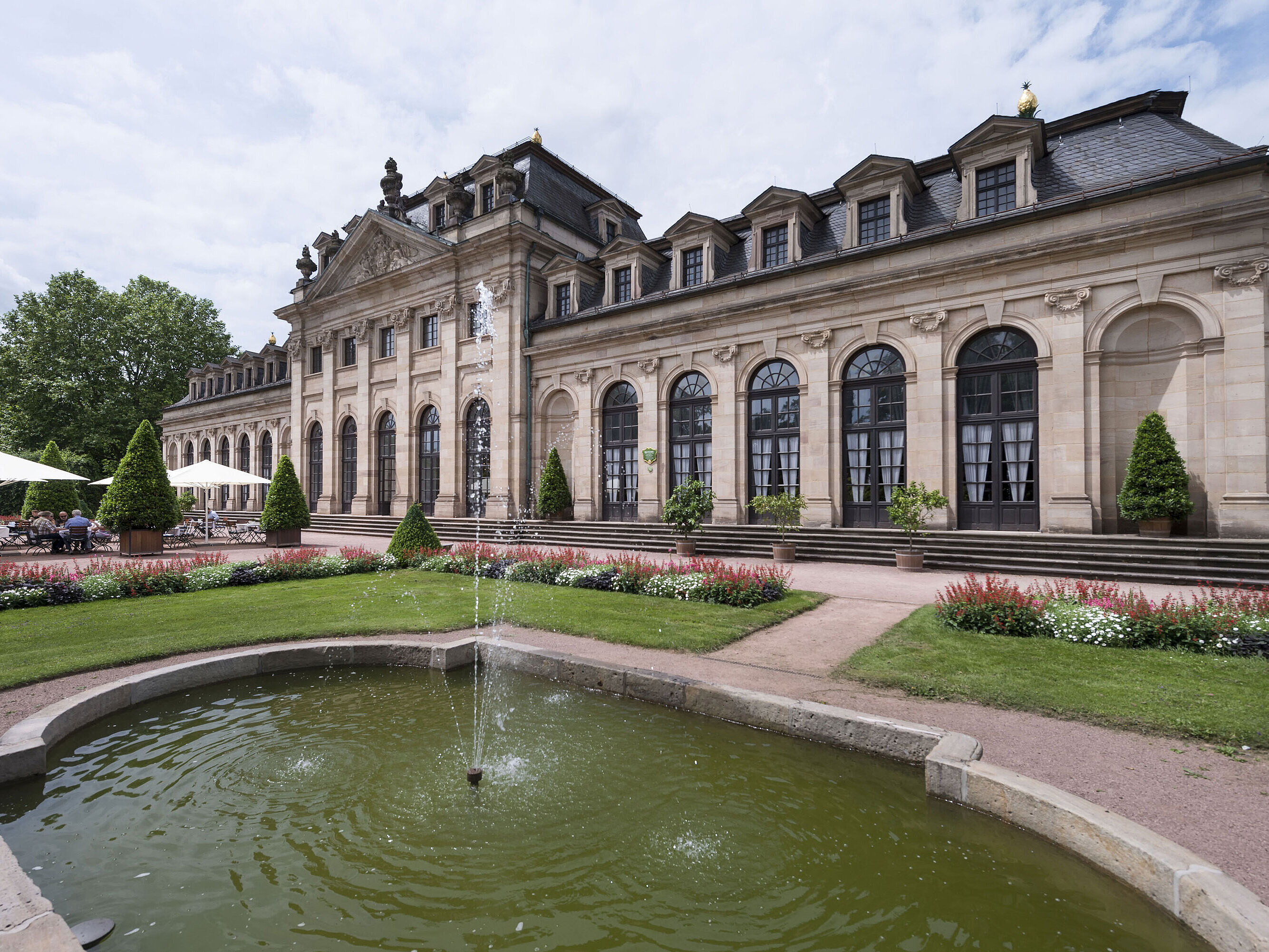 The baroque Orangerie Fulda with terrace, manicured garden, and historic fountain in the foreground.