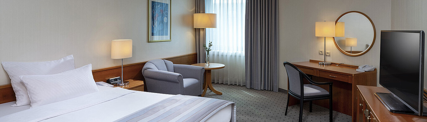 Cozy classic room with a large bed, desk, TV, and elegant decor at Maritim Hotel Hannover.