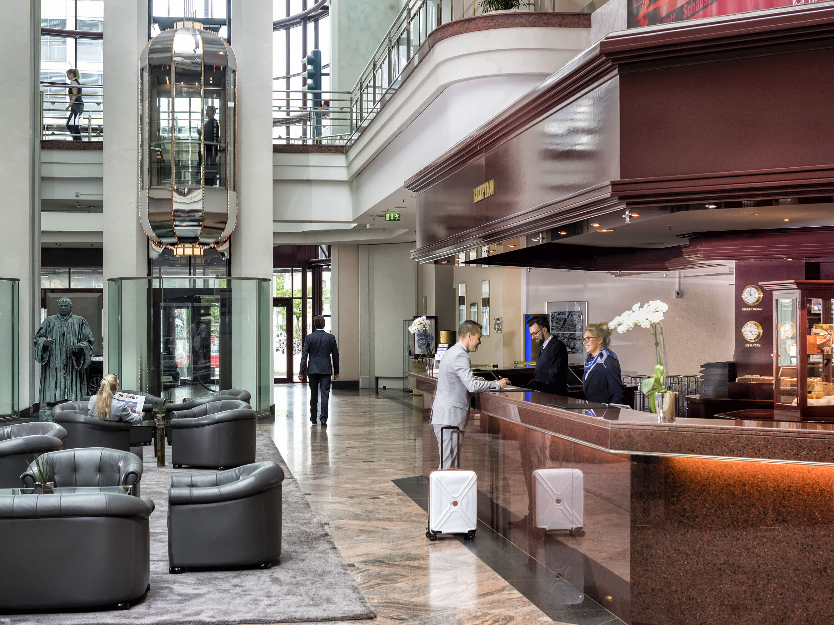 A guest checks in at the reception and is served by a friendly staff member.