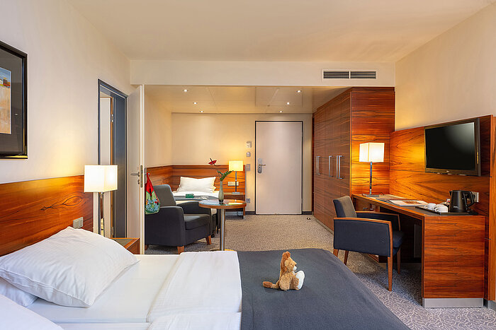 Modern family room with desk and cosy sitting area at the Maritim Hotel München