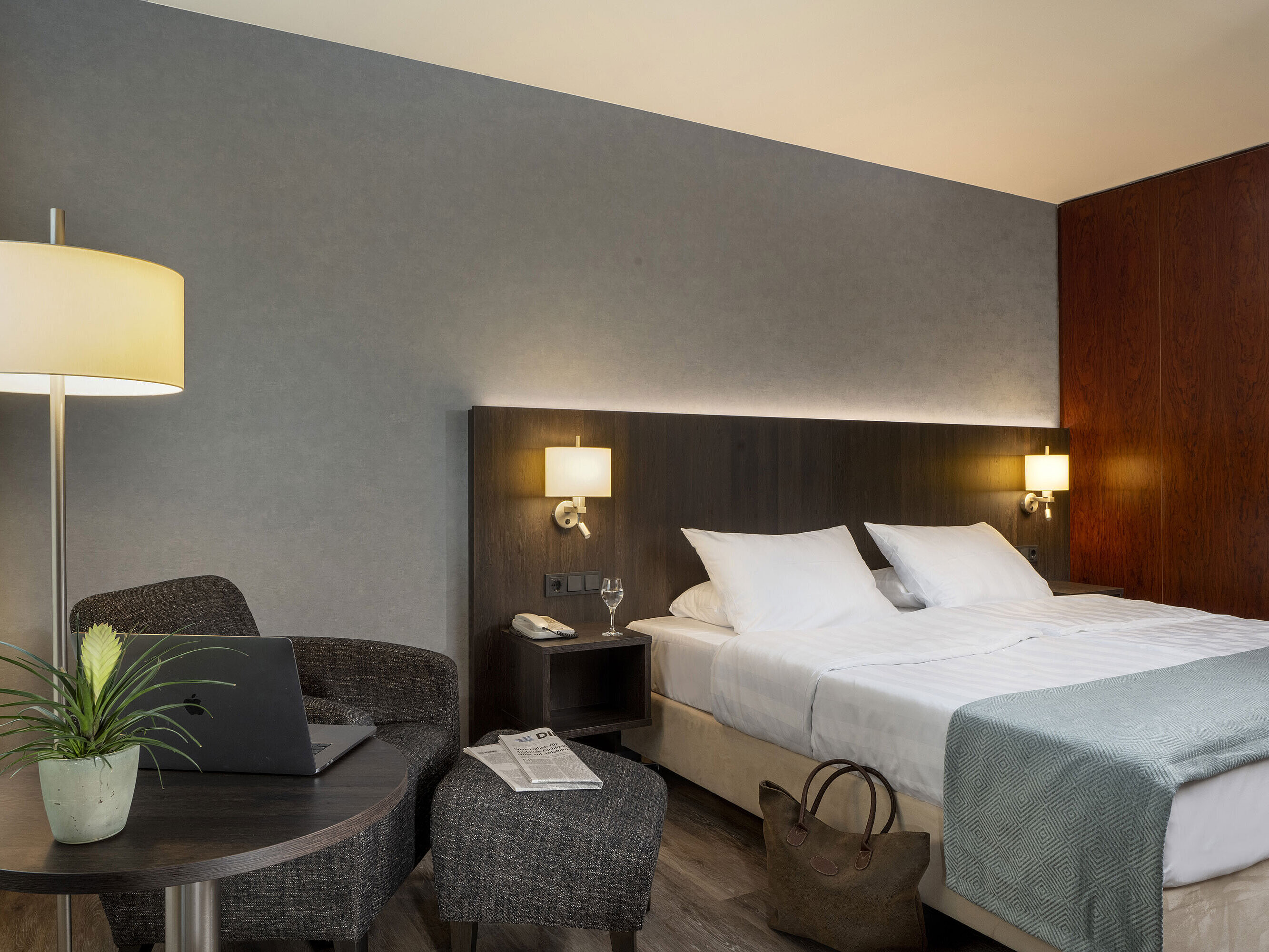 Modern double room at Maritim Hotel Bremen with cozy seating area, side table, vase, and inviting bed.