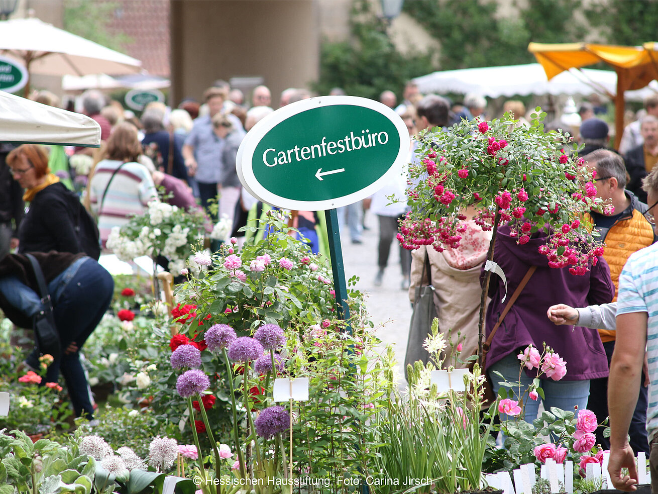 Visitors at garden festival with flower stalls in courtyard