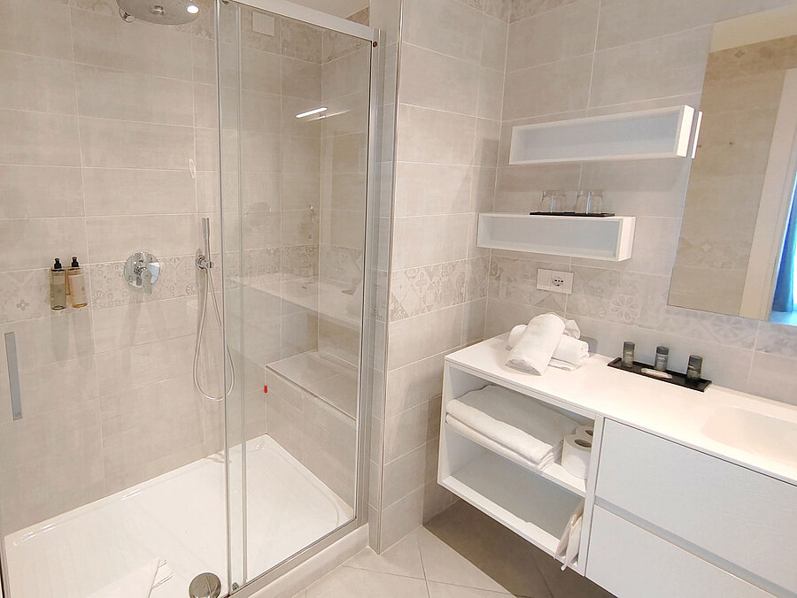 Spacious bathroom at Maritim Resort Calabria with rain shower, white furniture and open layout