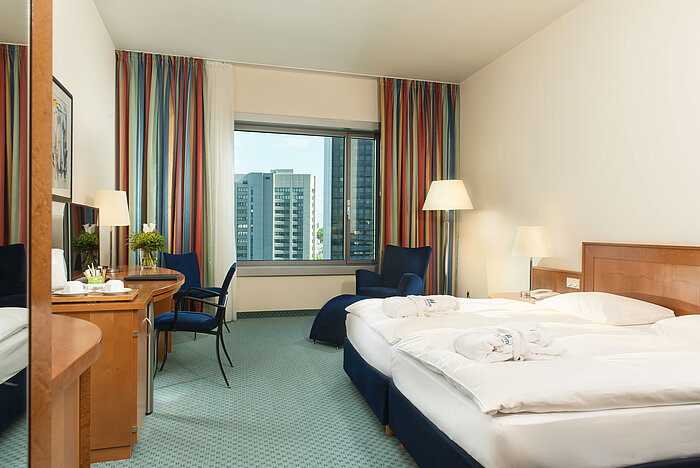 Superior room at Maritim Hotel Frankfurt with double bed, desk, seating area, and skyline view.