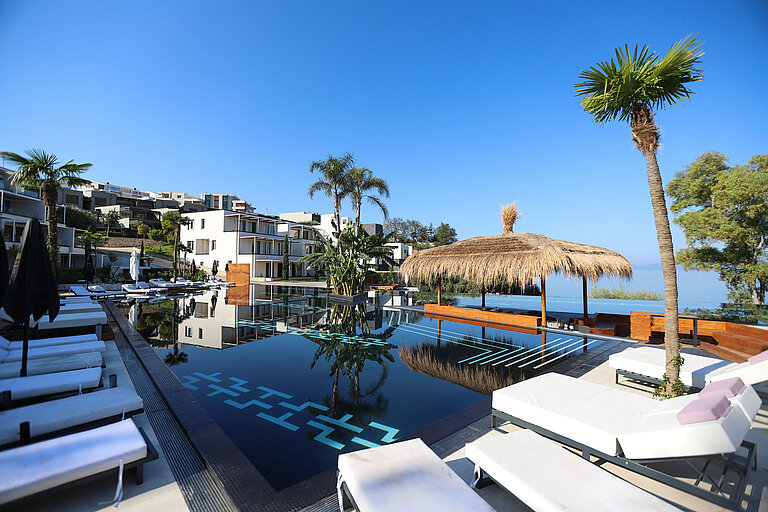 Exclusive pool area at Maritim Resort Marina Bay with palm trees, sun loungers and sea view