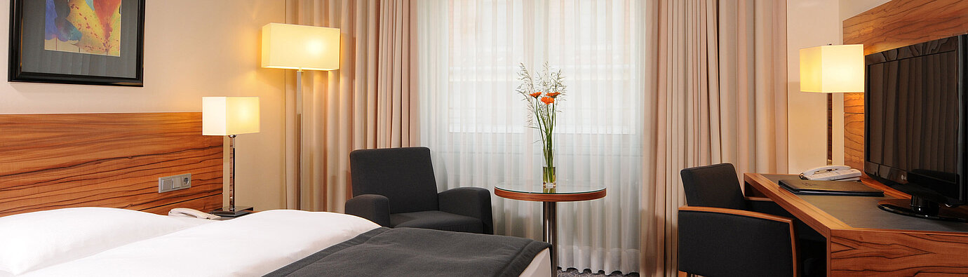 Modern single room with bed, armchairs and large window at Maritim Hotel Munich