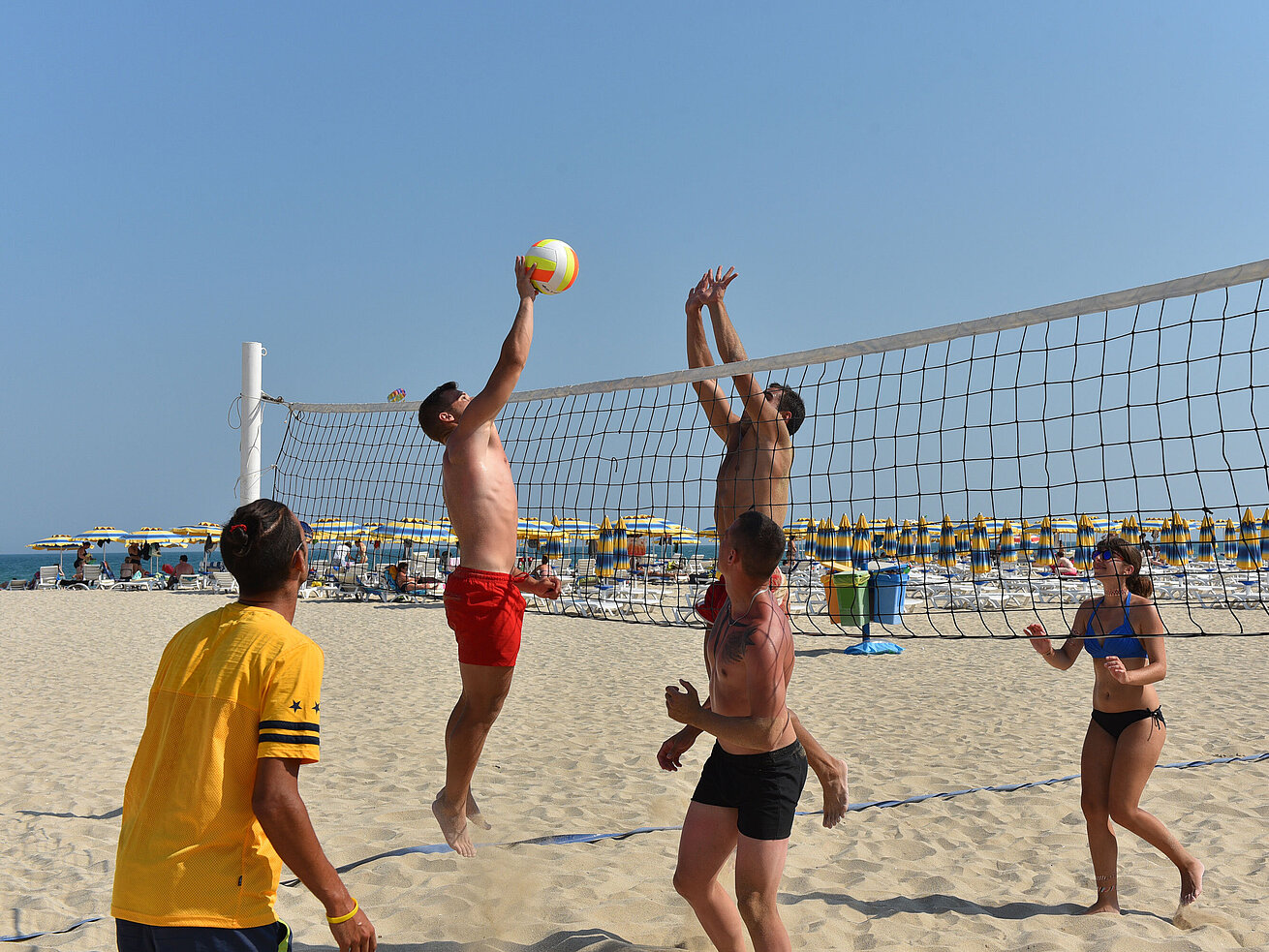 Beach volleyball match on the resort’s sandy beach with players at the net in sunny weather