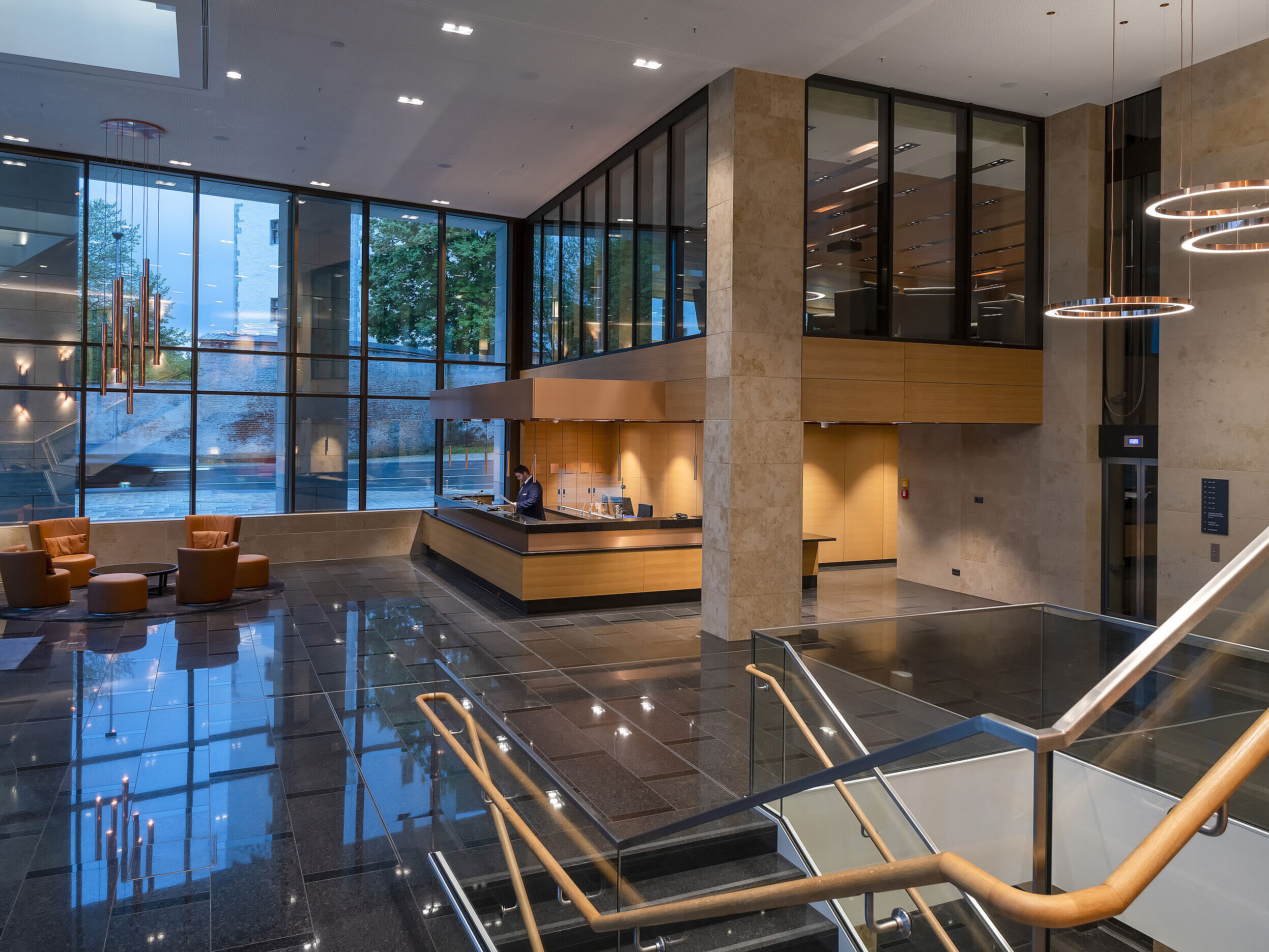 The modern lobby of Maritim Hotel Ingolstadt with high glass windows, reception, and cozy seating areas.