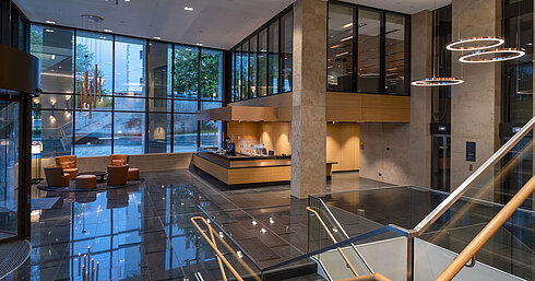 The modern lobby of Maritim Hotel Ingolstadt with high glass windows, reception, and cozy seating areas.